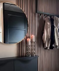 a room with a mirror, coat rack and candles on the shelf next to it