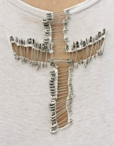 a man wearing a white t - shirt has a cross made out of metal pins