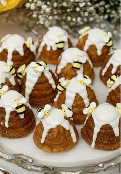 there are many small cakes with white icing on them and some bee decorations in the middle