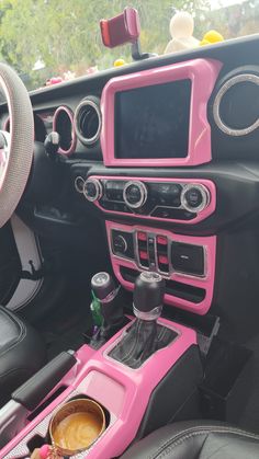 the interior of a car with pink trim and black leather seats, including an automatic cup holder