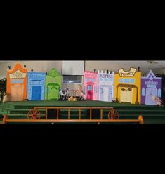 children's stage set up for an event with colorful doors and green carpeting