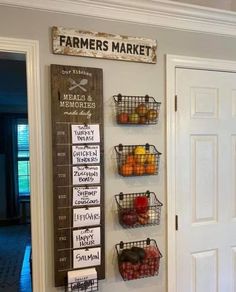 a wall hanging with baskets filled with fruits and vegetables next to a door that has a farmers market sign on it