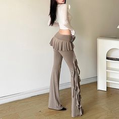 a woman standing in front of a white wall with her back to the camera and wearing high waist pants