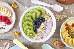 an assortment of fruits and cereals in bowls on top of a table with spoons