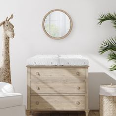 a baby's crib with a giraffe statue in the corner and a mirror on the wall