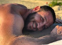 a man laying on top of a sandy beach