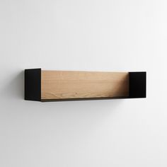 a wooden shelf mounted to the side of a wall next to a white wall with black trim