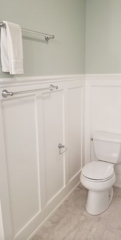 a white toilet sitting in a bathroom next to a sink and towel dispenser