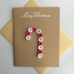 a christmas card with the letter j made out of buttons on top of a brown envelope