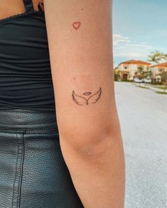 a woman's arm with a tattoo that has a bird on it and a heart in the middle