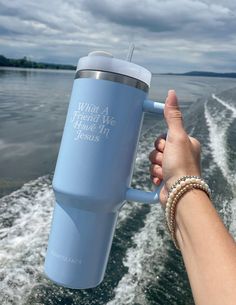 a person holding onto a blue coffee cup while on a boat in the water,