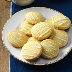 a white plate topped with yellow cookies next to a cup of coffee and saucer