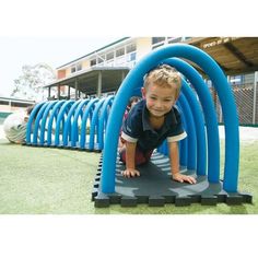 a little boy that is standing in front of a blue tube on the ground with grass