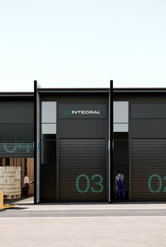 two men are standing in the doorways of an industrial building that has closed doors