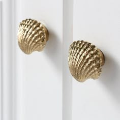 two gold scallop knobs on the side of a white door, one is closed