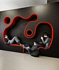 two people sitting on a red bench in front of a black wall with the shape of a heart