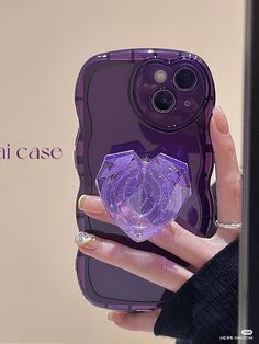 a person holding up a purple case with a heart shaped object in the middle of it