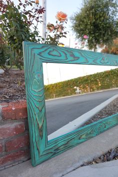 a wooden mirror sitting on the side of a road