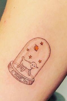 a small tattoo of a dog in a glass jar with stars on the side of it