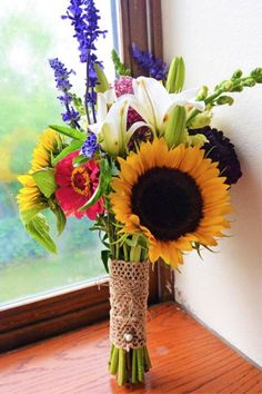 a vase filled with flowers sitting on top of a wooden table next to a window