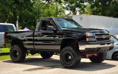 a black truck parked next to another white truck