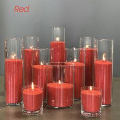 a group of red candles sitting on top of a table next to glasses filled with them