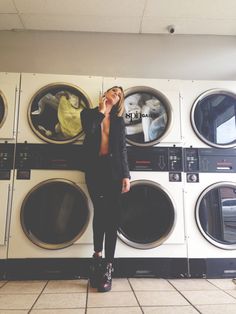 a woman standing in front of washers talking on her cell phone while looking up at the sky