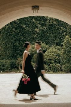 a man and woman walking under an archway