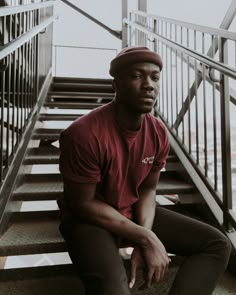 a man is sitting on the stairs with his hands in his pockets