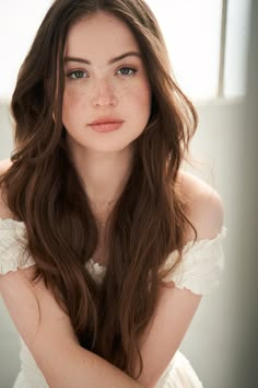 a woman with long brown hair wearing a white dress