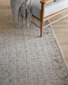 a chair sitting on top of a wooden floor next to a white rug covered in a blanket