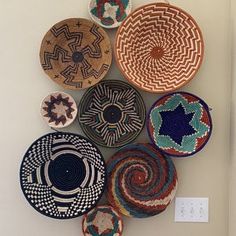 several baskets are hanging on the wall in different colors and sizes, each with a unique design