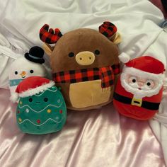 three stuffed animals sitting on top of a bed next to santa clause and snowman