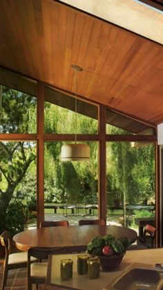 an open kitchen and dining room area with large windows, wood ceilinging and tile flooring