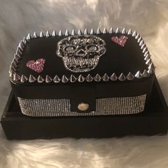 a black box with pink and silver diapered skulls on the front, sitting on a white furnishing