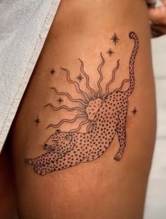 a woman with a tattoo on her thigh that has a leopard and sun in it