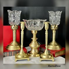 three glass candlesticks sitting on top of books