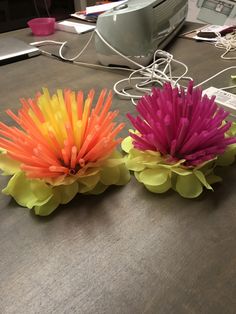 three paper flowers sitting on top of a table