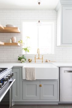 a kitchen with gray cabinets and white counter tops is pictured in this image, there are shelves on the wall above the sink