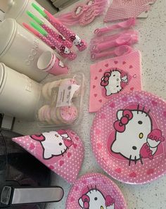 hello kitty plates, cups and utensils are laid out on a counter top