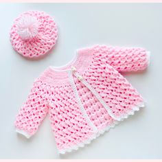 a pink knitted sweater, hat and booties