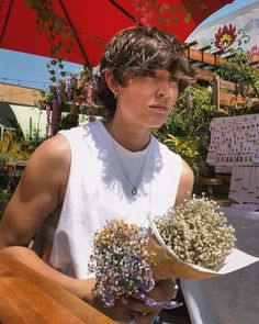 a woman holding flowers in her hands under an umbrella