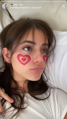 a woman laying in bed with her face painted like a heart and the words i love you written on her cheek