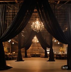 a room with black drapes and chandeliers