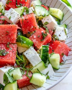 a bowl filled with watermelon, cucumber and feta cheese salad