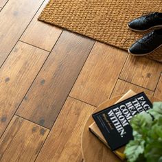 a pair of black shoes sitting on top of a wooden floor next to a plant