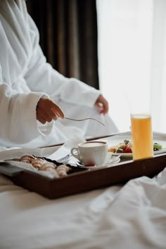 a person sitting at a table with food and drinks on it, in front of a window