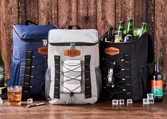 three different types of backpacks with bottles and glasses on the table next to them