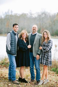 a family posing for a photo in front of a lake with their arms around each other