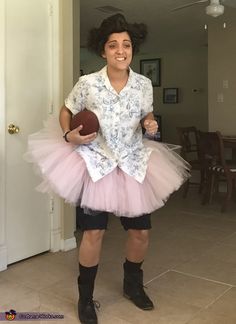 a woman in a tutu skirt and shirt holding a football while standing next to a door